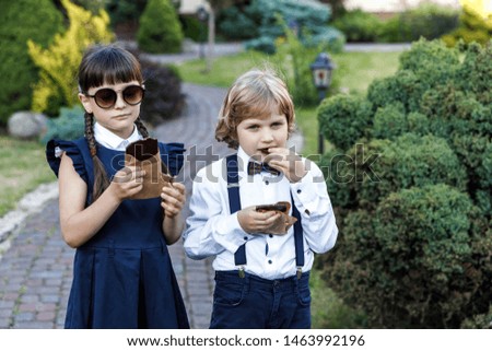 Cute blond guy and cute girl, school year fun time outdoors. Children eat chocolate.