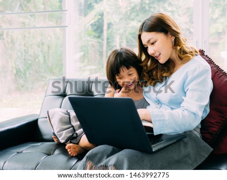 Child and younger mum looking something in laptop and feel happy together during their holiday at home