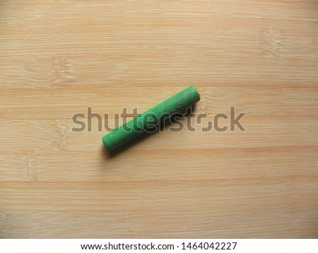 Green color oil pastel stick kept on wooden table