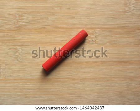 Red color oil pastel stick kept on wooden table