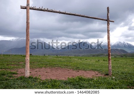 Rustic field with a wooden gate for playing football on the background of a mountain ridge with snow-capped peaks. Naryn Region