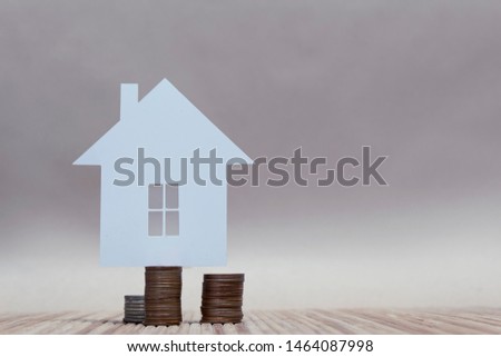 The concept of home from paper on a stack of coins. Horizontal composition