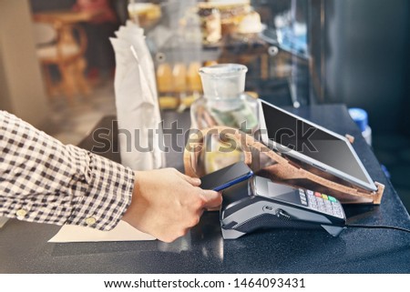 Close up view on contactless payment through the POS terminal in cafe. Cashbox concept. Paying with smartphone. paying with smartphone in shop using NFC technology. commerce. Toned picture