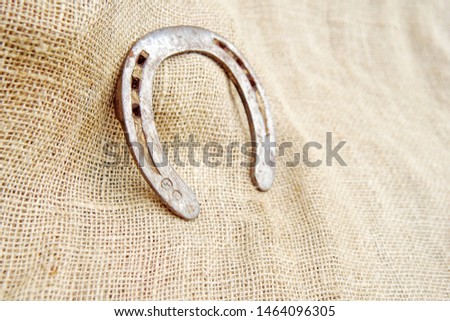 macro closeup of an old rusty aged weathered horseshoe horse shoe on canvas burlap fabric symbol lucky charm of luck fortune and success with space for text 