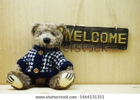 Welcome Sign and Teddy bear on wooden background