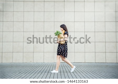 The girl comes with a bag with a baguette near the supermarket. The concept of shopping, eco shopping, lifestyle.