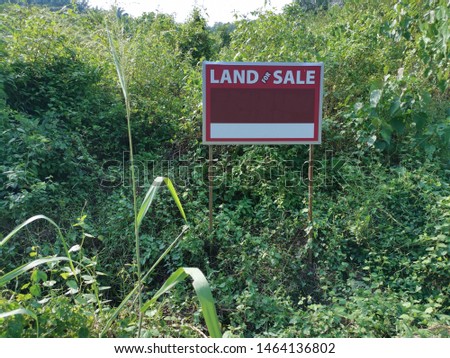 land for sale signboard located at the wild bushy empty land.