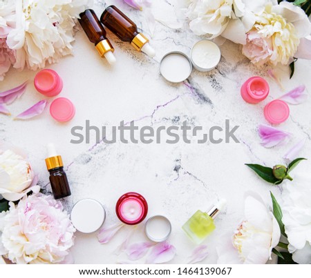 Flat lay composition with peony flowers and natural cosmetic on marble background

