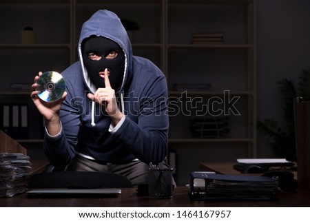 Male thief in balaclava in the office night time 