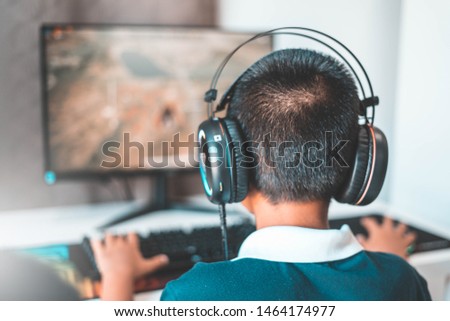 Asian boy wearing headphones playing computer games-image.