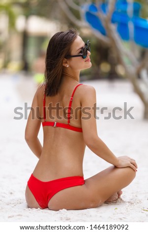 Beautiful woman in a red bathing suit is burning by the pool