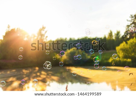 beautiful background with soap bubbles at sunset lake, horizontal
