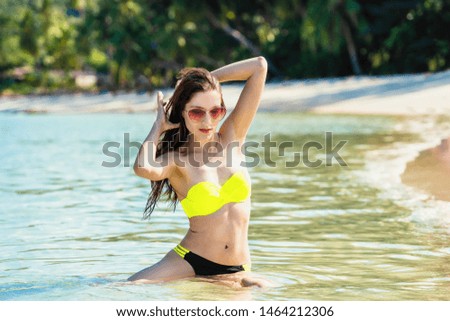 Summer travel background concept. Happy woman sitting in water on white sand beach vacation.