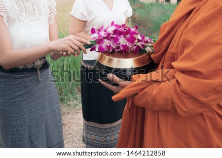 The monk walked to get alms in the morning. Two girls offering flowers to the monksใ