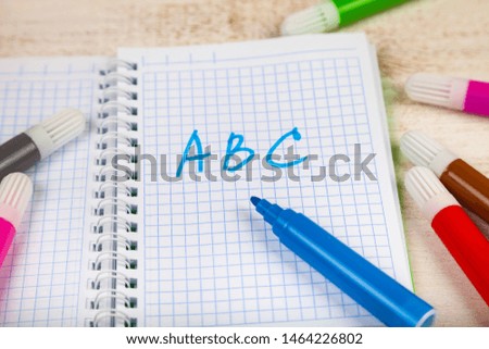 Back to school. Items for the school on a wooden table. Markers and notebook with letters ABC.