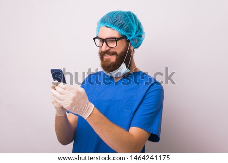 Photo of young doctor in uniform using smartphone