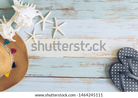 Cute grey polkadot slippers  with star fish and hat on blue grunge wooden background feel like summer season and traveling to the beach.