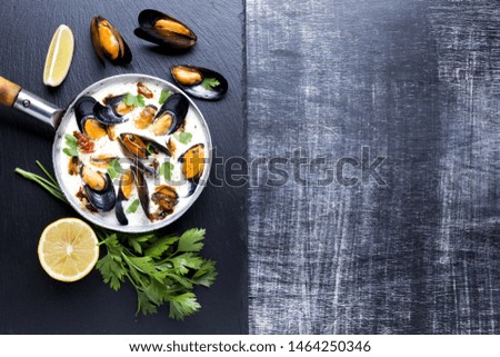 Flat-lay mussels in white sauce on slate with copyspace