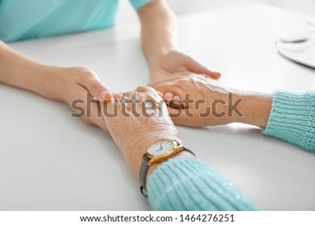 Doctor supporting elderly woman in clinic, closeup
