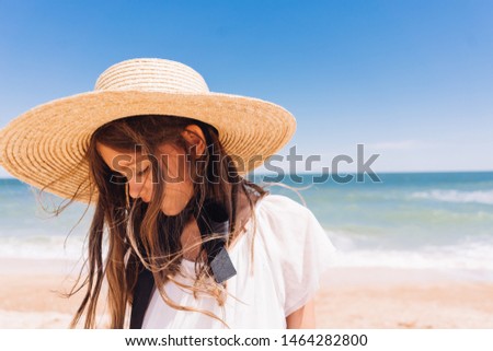 beautiful girl in white dress in a hat on the sea with sandy beach