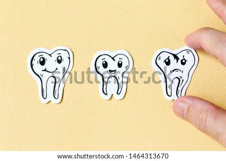 Set of cute little healthy white teeth on yellow background. A man holds a bad tooth.