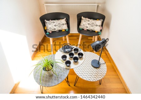 Stylish Interior Decoration of a Cosy Corner of a House with Cast Iron Teapot, Cups, Geometric Tables and Chairs