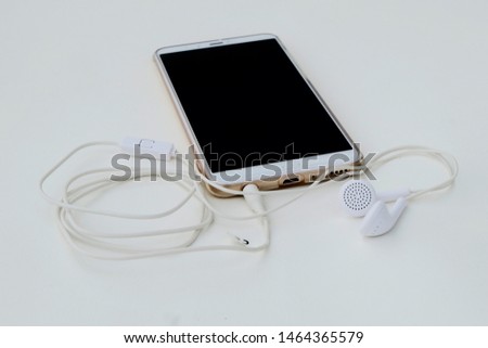 White headphone cable, white smartphone, white background and smart phone headphones inserted together