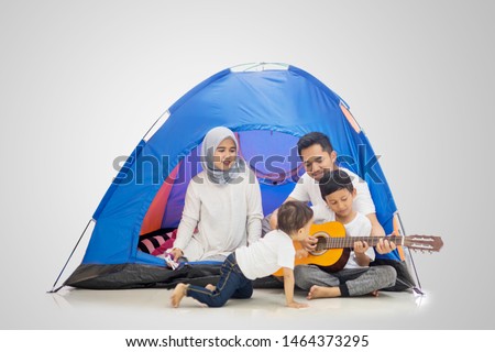Picture of a Muslim family playing a guitar and singing in the tent while camping in the studio, isolated on white background