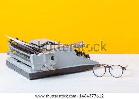 Workplace of the manager of the secretary and business typewriter and glasses are on the table on a yellow background. Office work concept.