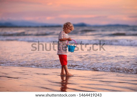 Child playing on ocean beach. Kid jumping in the waves at sunset. Sea vacation for family with kids. Little boy running on tropical beach of exotic island during summer holiday. 