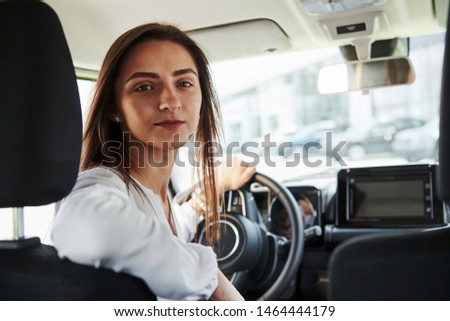 Cheerful female driver is in her new car. Interior of modern automobile.