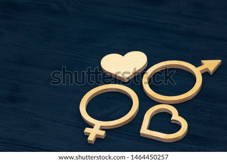 A symbol of gender equality made of plywood. Black wooden background. Male and female symbolsGender