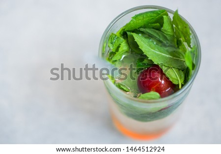 colorful fresh coctail with mint leafs and cherry plum inside glass