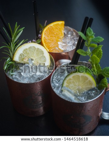 This picture shows 3 copper cups filled to the brim with ice and alcohol and garnished with citrus fruits.