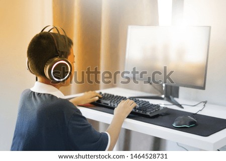 Asian boy wearing headphones playing computer games-image.focus around his head.