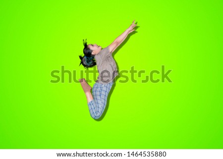 Picture of Asian woman performing a jump in the studio with green screen background