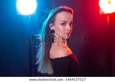 Nightclub, nightlife and people concept - Young woman posing in the dark