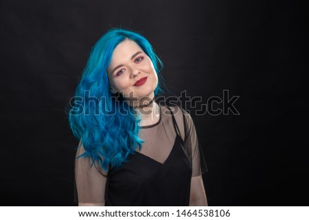 Style, fashion and hair concept - close-up portrait of young woman in black dress with blue hair on black background