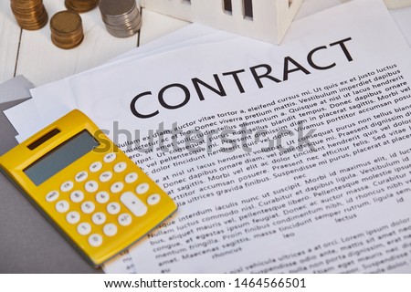 metal coins, yellow calculator near contract, real estate concept