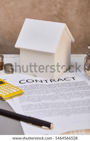 house model, coins, calculator near contract and moneybox, real estate concept
