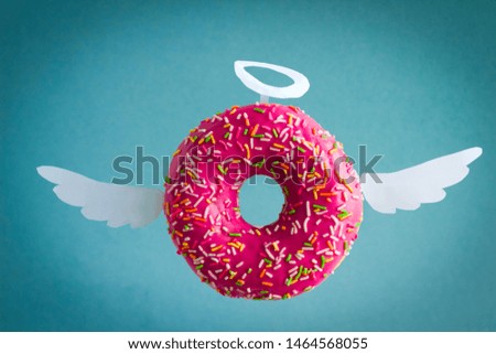 sweet pink  donut with white paper wings and nimbus on a  blue background