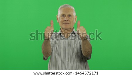 Senior man show thumb up and smiles. Handsome old man on chroma key background. Positive elderly grandfather in grey shirt. 