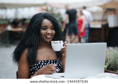 Charming woman with beautiful smile reading good news on laptop during rest in coffee shop, happy ethnic female  relaxing in cafe during free time.