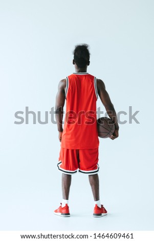 back view of african american basketball player holding ball on grey background
