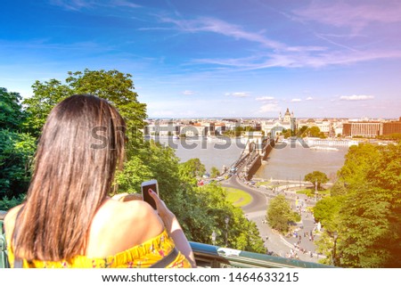 A young woman taking pictures of Budapest, Hungary with her phone.