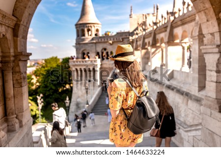 A happy young woman enjoying her trip to the Castle of Budapest in Hungary while taking pictures and selfies.