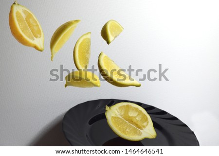 pieces of lemon flying in the air on the black plate with a white background Royalty-Free Stock Photo #1464646541