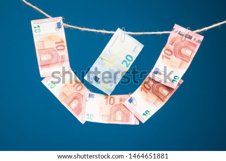 Euro bills hung in the form of a necklace on a rope, joined by clips.