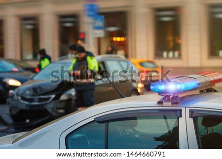 Police patrol cars with red and blue flashing siren on the road.  Automobile collision on the road. Investigating car accident, road crash. Police officer on background. Police vehicle