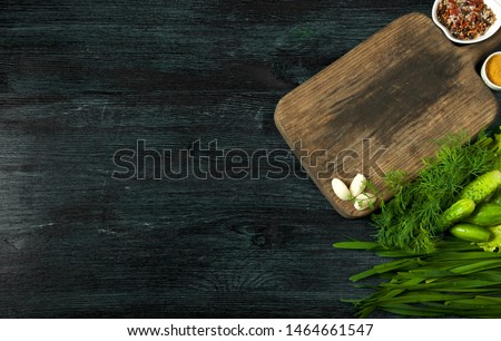 Salad with vegetables. View from above. Fresh salad in a plate on a dark background. Garlic, tomato, cucumber, dill and onion in a dish of dark surface. Copy space.
